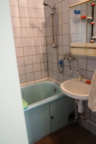 Общее состояние ванной до ремонта: старая, много раз крашенная ванна, старый умывальник с зеркаолом, плитка на полу поверх линолеума и старый кафель на стенах