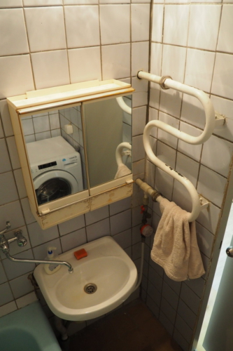 Старый полотенцесушитель, умывальник и зеркало в ванной