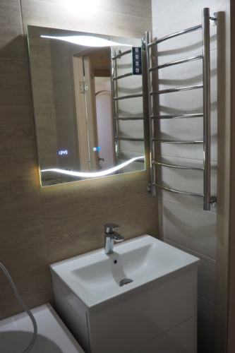 Зеркало с подсветкой, умывальники и полотенцесушитель в отремонтированной ванной