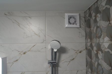 Перенесенное отверстие вентиляции с установленным вентилятором в ванной после ремонта