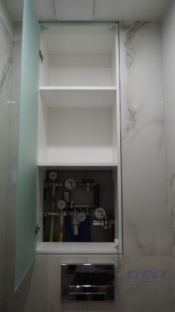 Туалет после ремонта со встроенным белым шкафчиком и стеклянной дверцей